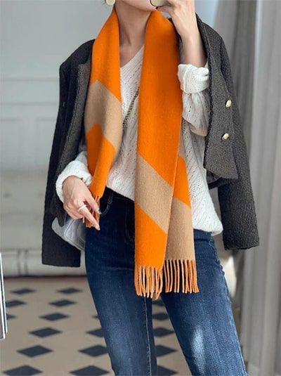 Women's orange and camel cashmere scarf paired with jeans and white sweater